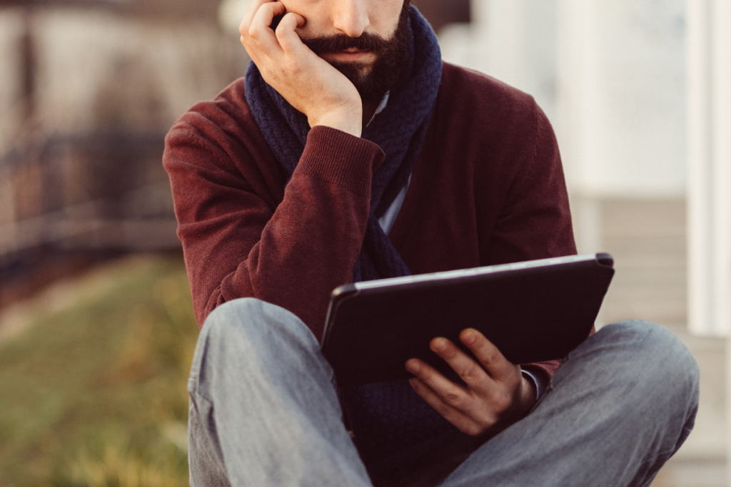 Sitzende Person mit Bart und Tablet in der Hand